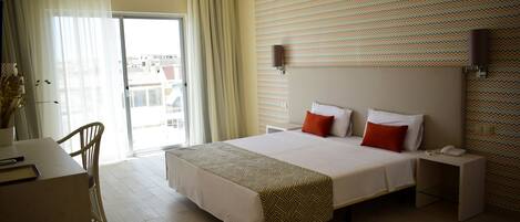 Habitación de hotel con una cama grande, un escritorio, una silla, una mesita de noche y vistas por la ventana.