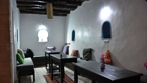 A cozy room with a sofa, a bench, a table, and a patterned rug. - Apparently familial  (Ancien Médina)