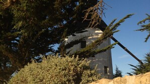 A stone wall with a windmill partially obscured by trees.