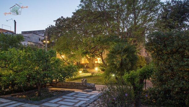 Un sendero en un jardín que lleva a un edificio con una entrada bien iluminada.