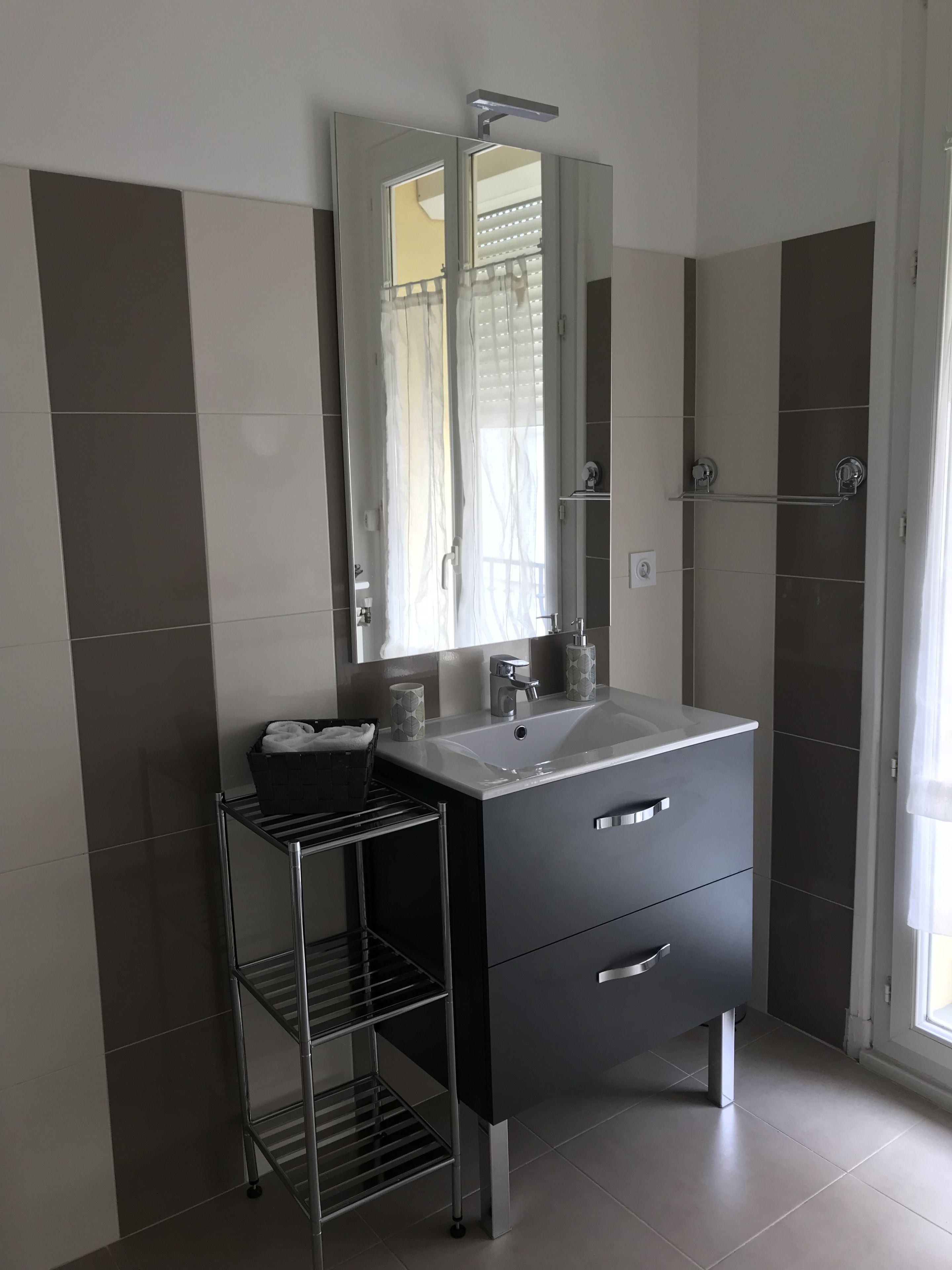 A modern bathroom with a large mirror, a sink, and a towel rack.