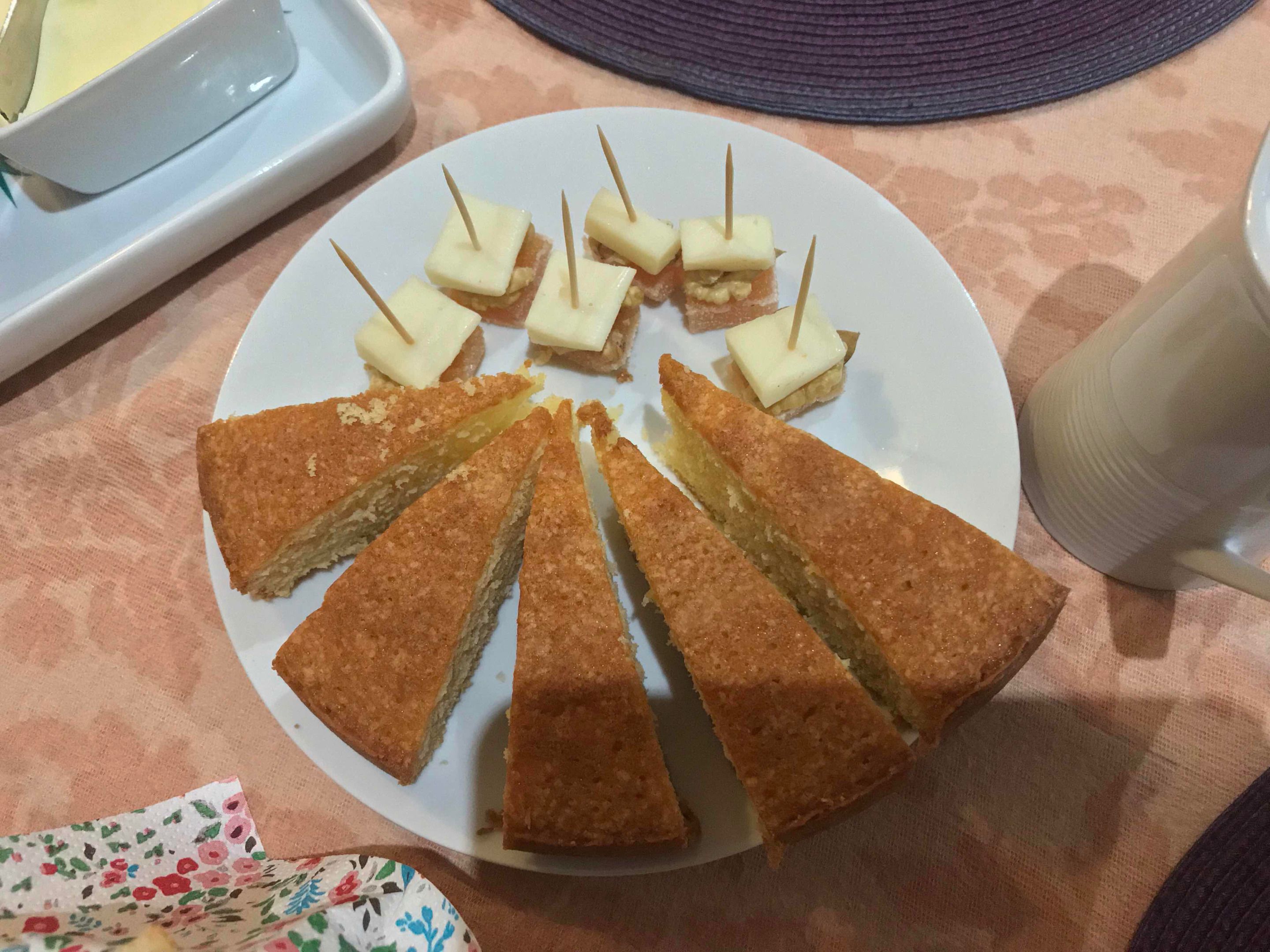 Een bord met een plak cake en verschillende kleine, vierkante stukjes cake met satéprikkers.
