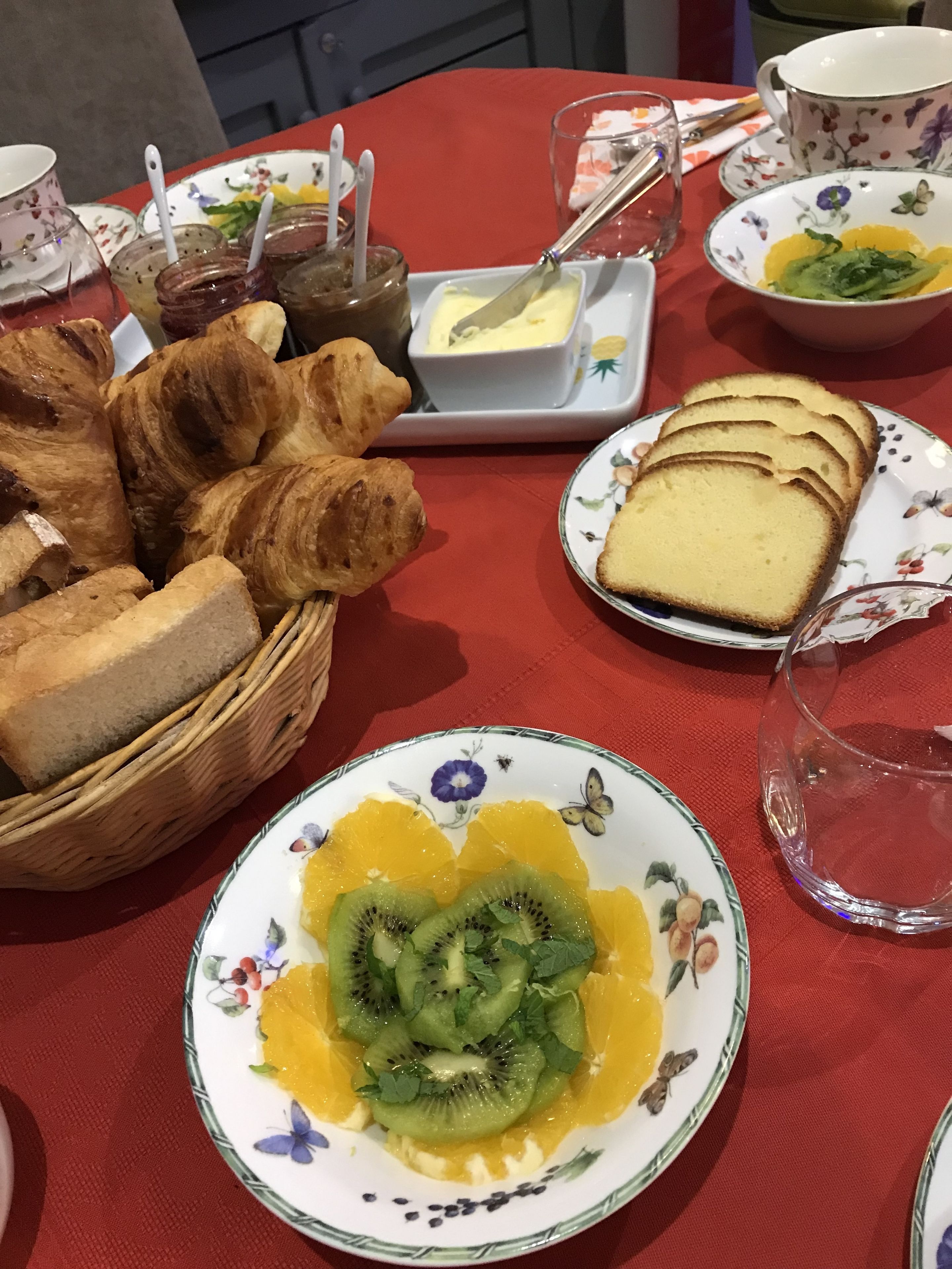 Ein Tisch mit Croissants, Brotscheiben, einer Schüssel mit Kiwis und Orangenschnitten und einer kleinen Butterportion.