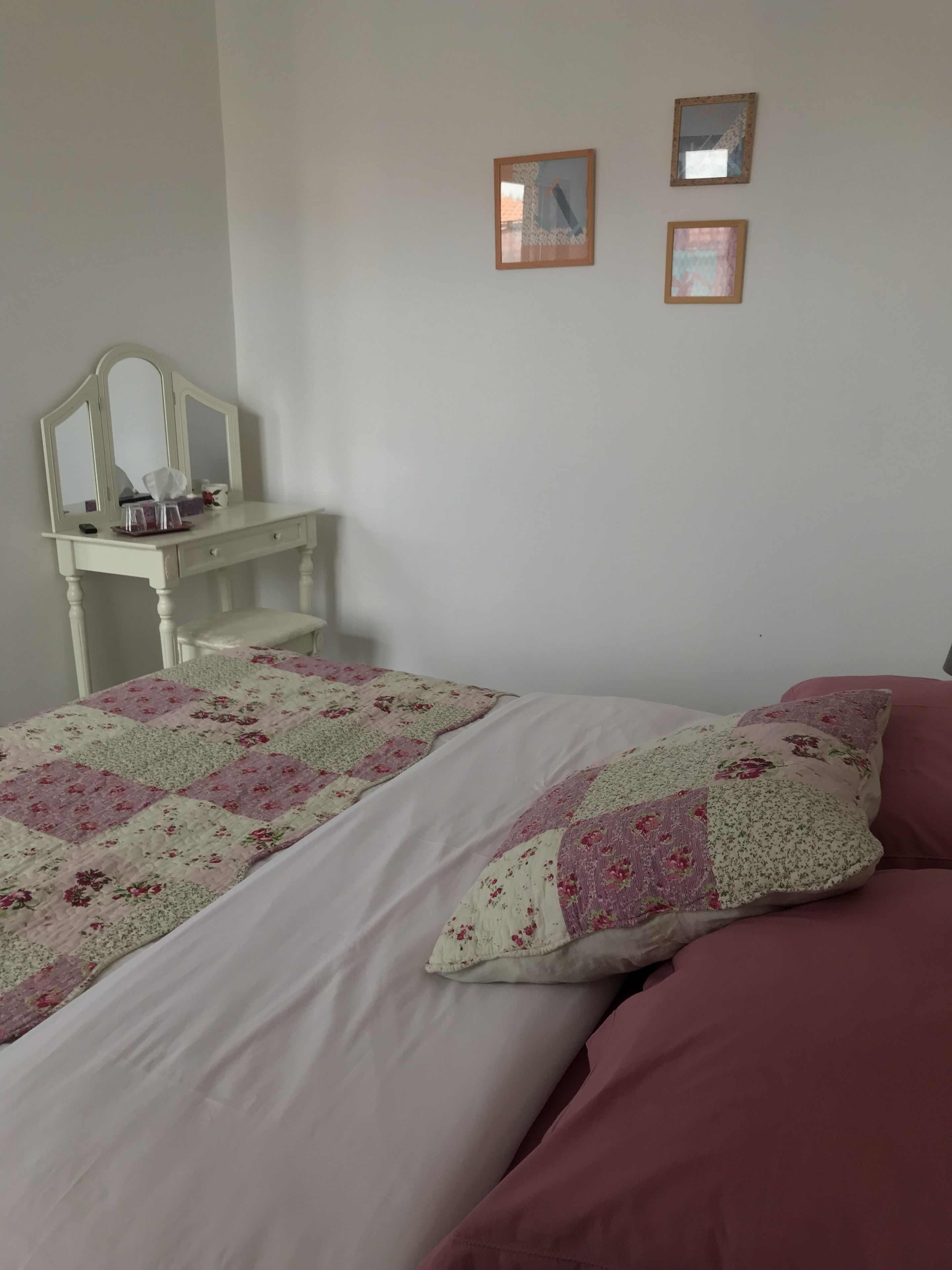 Een slaapkamer met een bed, een nachtkastje, een kaptafel en twee spiegelwanden.