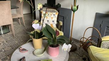 Een kamer met een ronde tafel, stoelen, een bank en decoratieve planten.