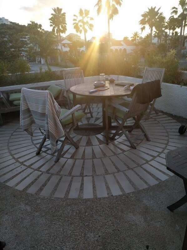 A round wooden table with four chairs, surrounded by a patterned floor.