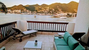 A patio with a green sofa, a lounge chair, and a small table. - Sint Maarten 2 Bedrooms Simpson Bay (Simpson Bay)