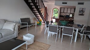 A living room with a sofa, coffee table, and chairs. There is a staircase leading to another level. - Sint Maarten 2 Bedrooms Simpson Bay (Simpson Bay)
