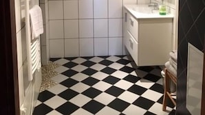 A bathroom with a checkered floor, white tiles, a sink, and a mirror. - Chambres d'Hôtes les Hirondelles (Folkling)