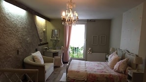 A bedroom with a large bed, a chair, a desk, and a chandelier. - Chambres d'Hôtes les Hirondelles (Folkling)