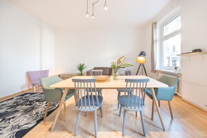 Un área de comedor con una mesa de madera, cuatro sillas, un tapete y una ventana con vistas.