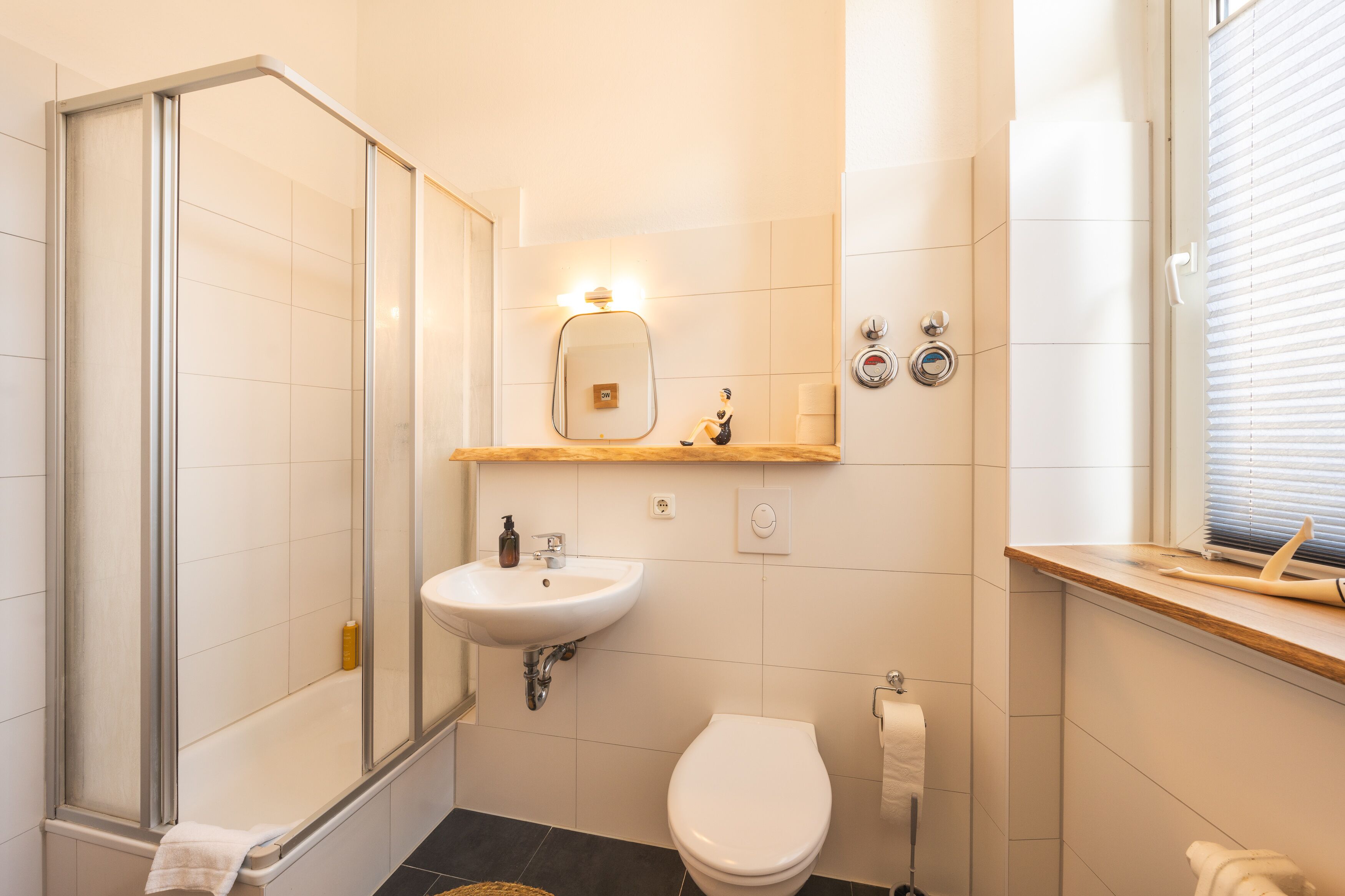 Un baño con cabina de ducha de vidrio, un lavabo con espejo y un inodoro.