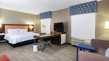 A hotel room with a bed, desk, chair, and a television.