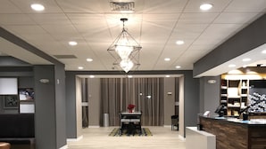 Un moderno vestíbulo de hotel con un comedor central, una recepción y una alfombra estampada.