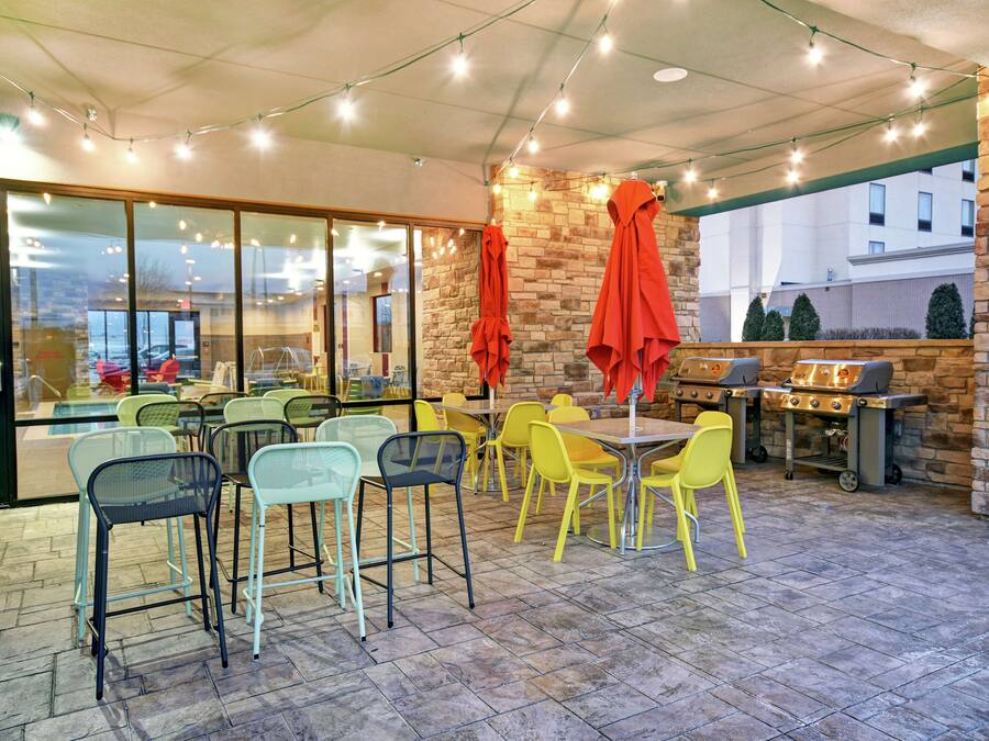 An outdoor patio area with tables and chairs, a barbecue grill, and string lights.