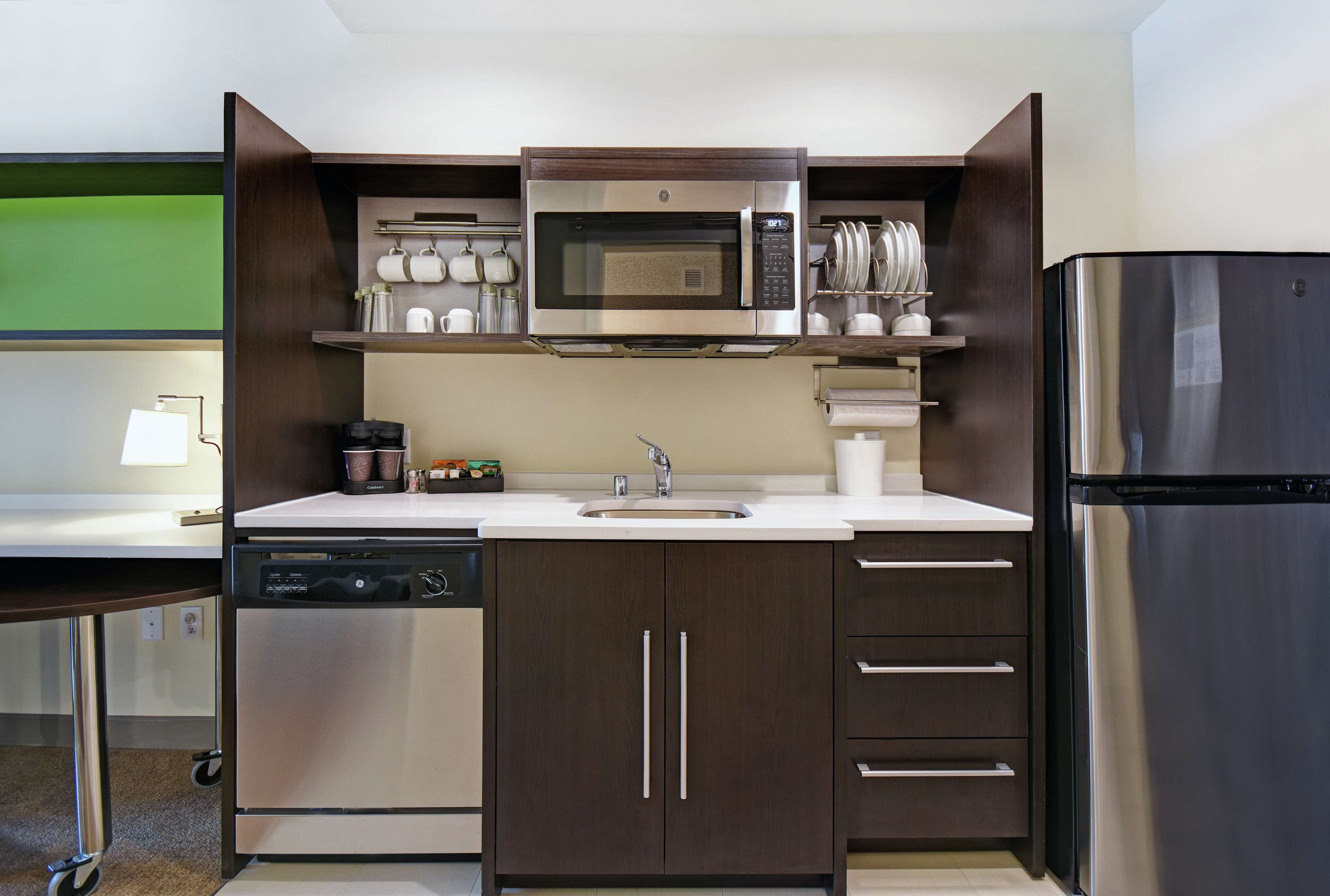 Una cocina moderna con microondas de acero inoxidable, lavavajillas y refrigerador.