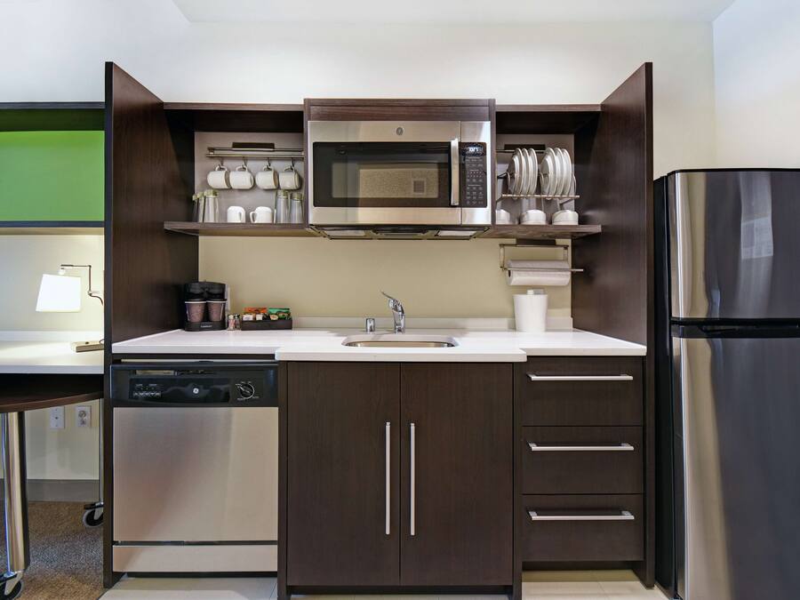 Una cocina moderna con microondas de acero inoxidable, lavavajillas y refrigerador.