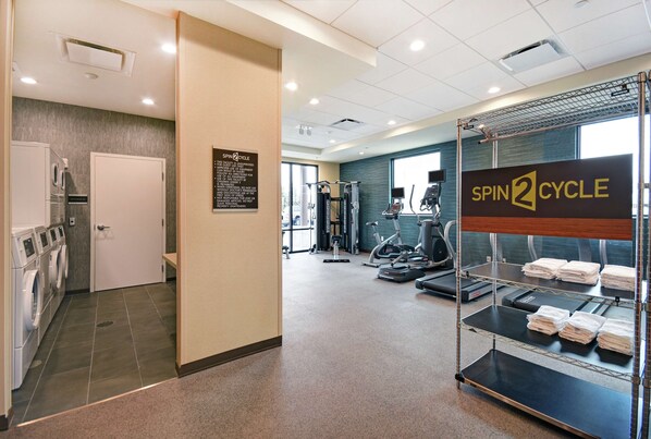 A gym with exercise equipment, a laundry area, and a sign for Spin2Cycle.