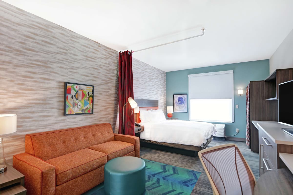 Une chambre d’hôtel avec un canapé, un lit, un bureau et une chaise.