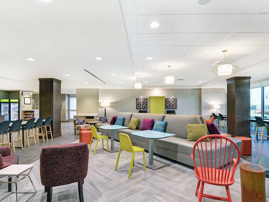 A modern lounge area with a sofa, chairs, tables, and a bar area.