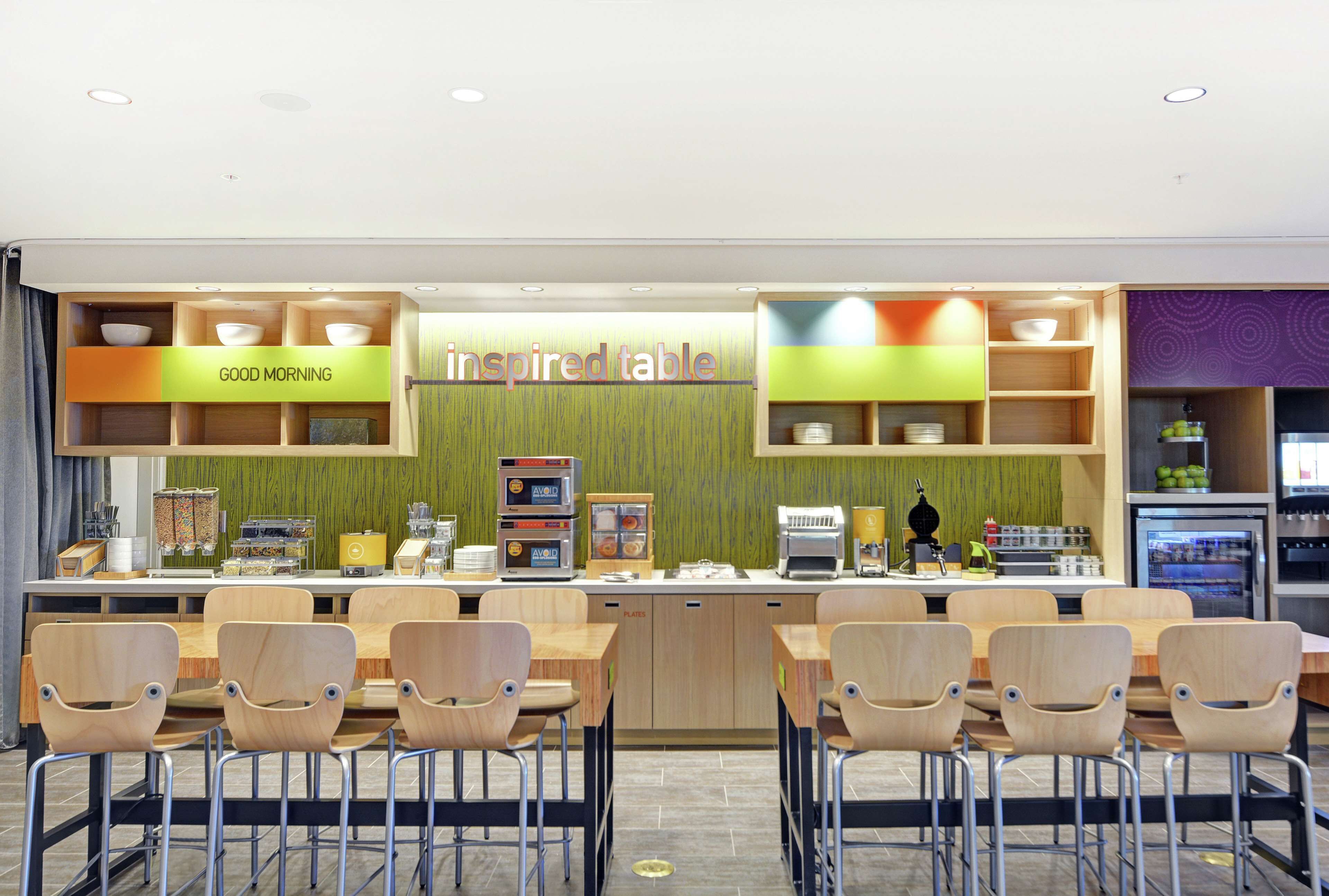 Un espace dédié au petit-déjeuner, agrémenté d’une pancarte « Bonjour », d’une autre indiquant « Table d’inspiration », et où une variété de produits pour le petit-déjeuner sont présentés.