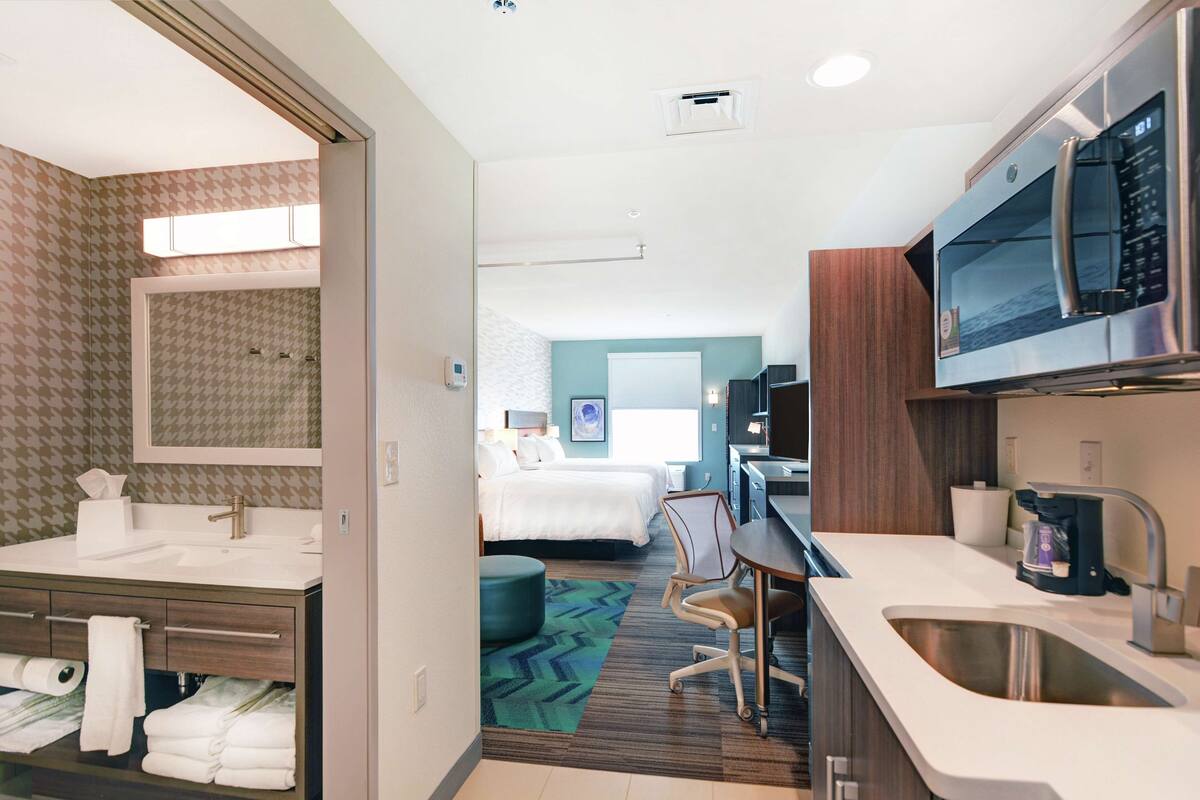 Une chambre d’hôtel avec salle de bain, kitchenette et un lit.