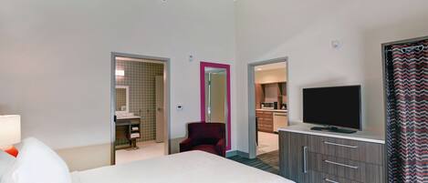 Una habitación de hotel con cama, televisión, escritorio y una silla.