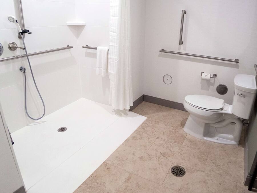 A modern bathroom with a walk-in shower, grab bars, a toilet, and a bidet.