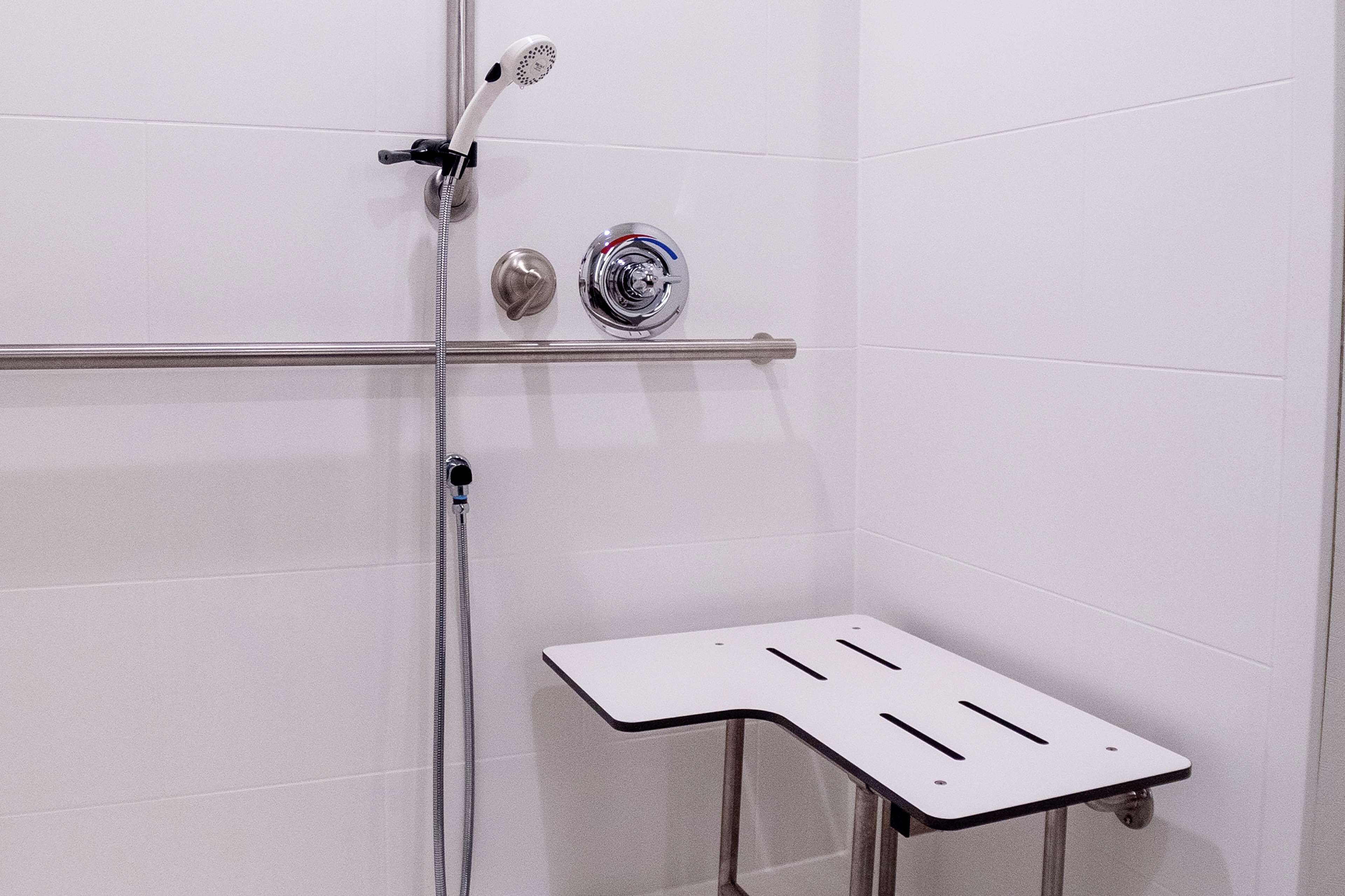 Un espace douche équipé d’un pommeau de douche à main, d’un robinet mural et d’une manette de réglage.