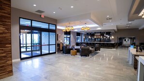 Eine geräumige Lobby mit Barbereich, Sitzgelegenheiten und großen Fenstern.
