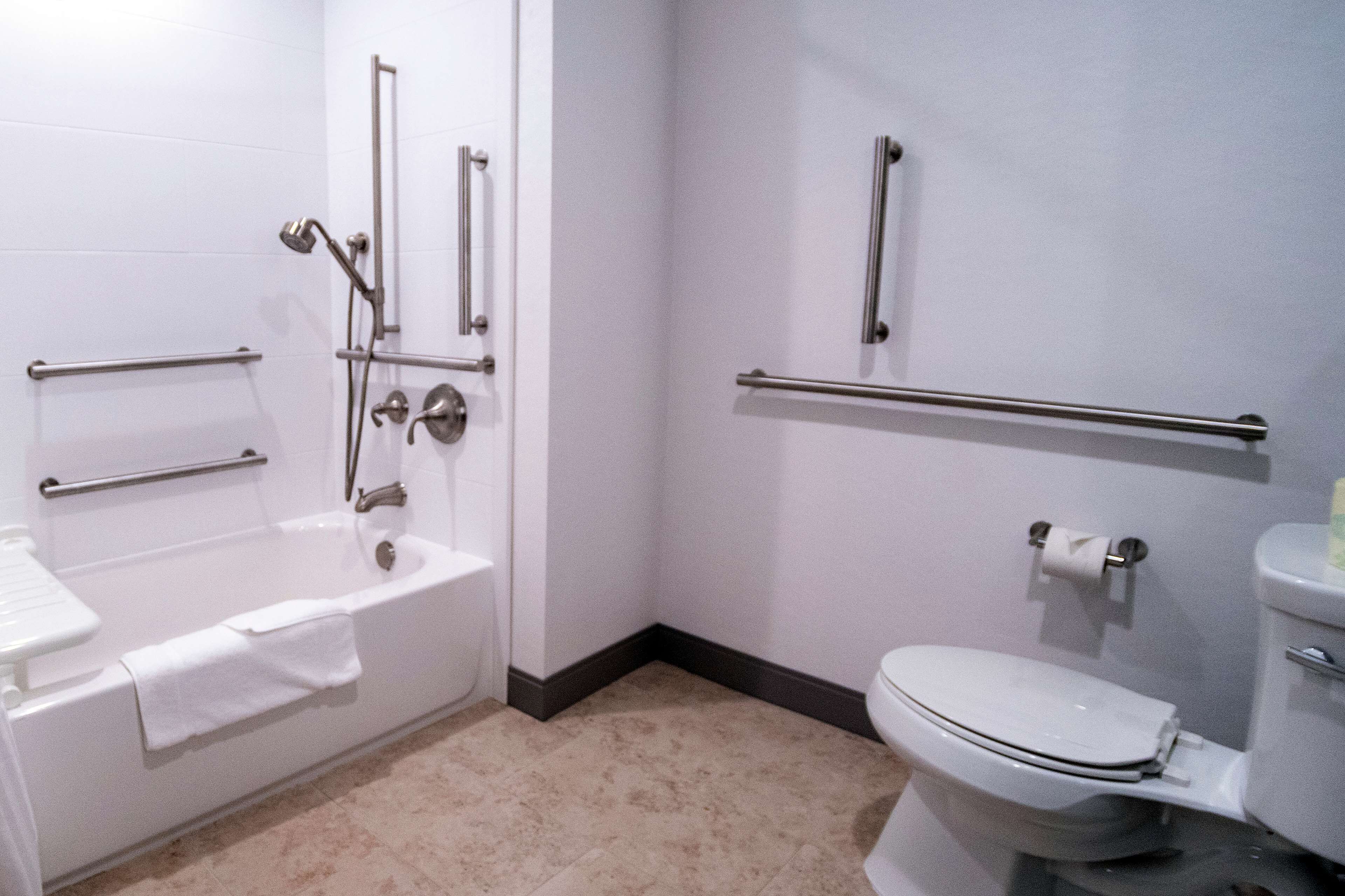 A bathroom with a bathtub, toilet, and grab bars.