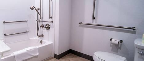 A bathroom with a bathtub, toilet, and grab bars.