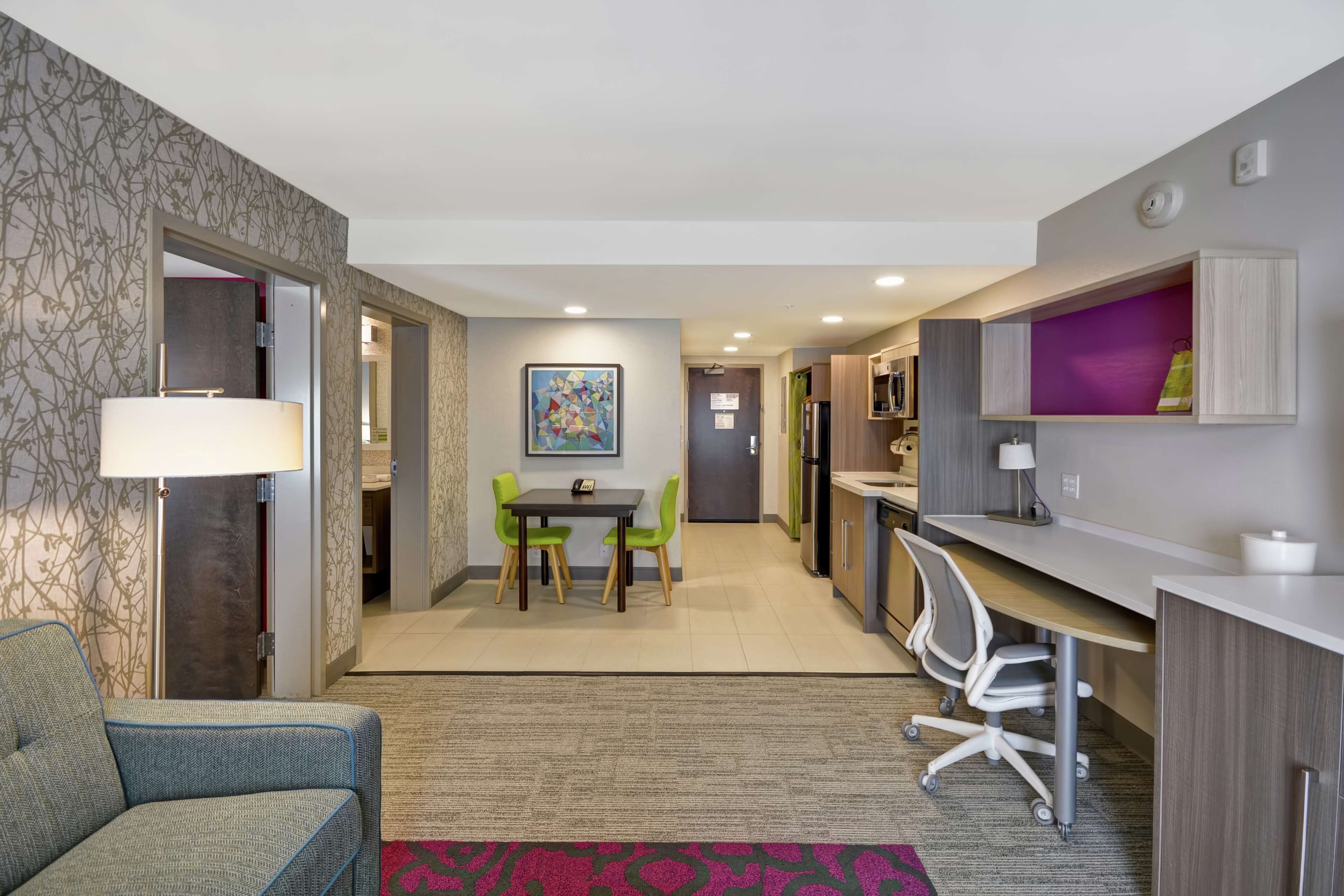 A modern hotel room with a dining area, a desk, and a chair.