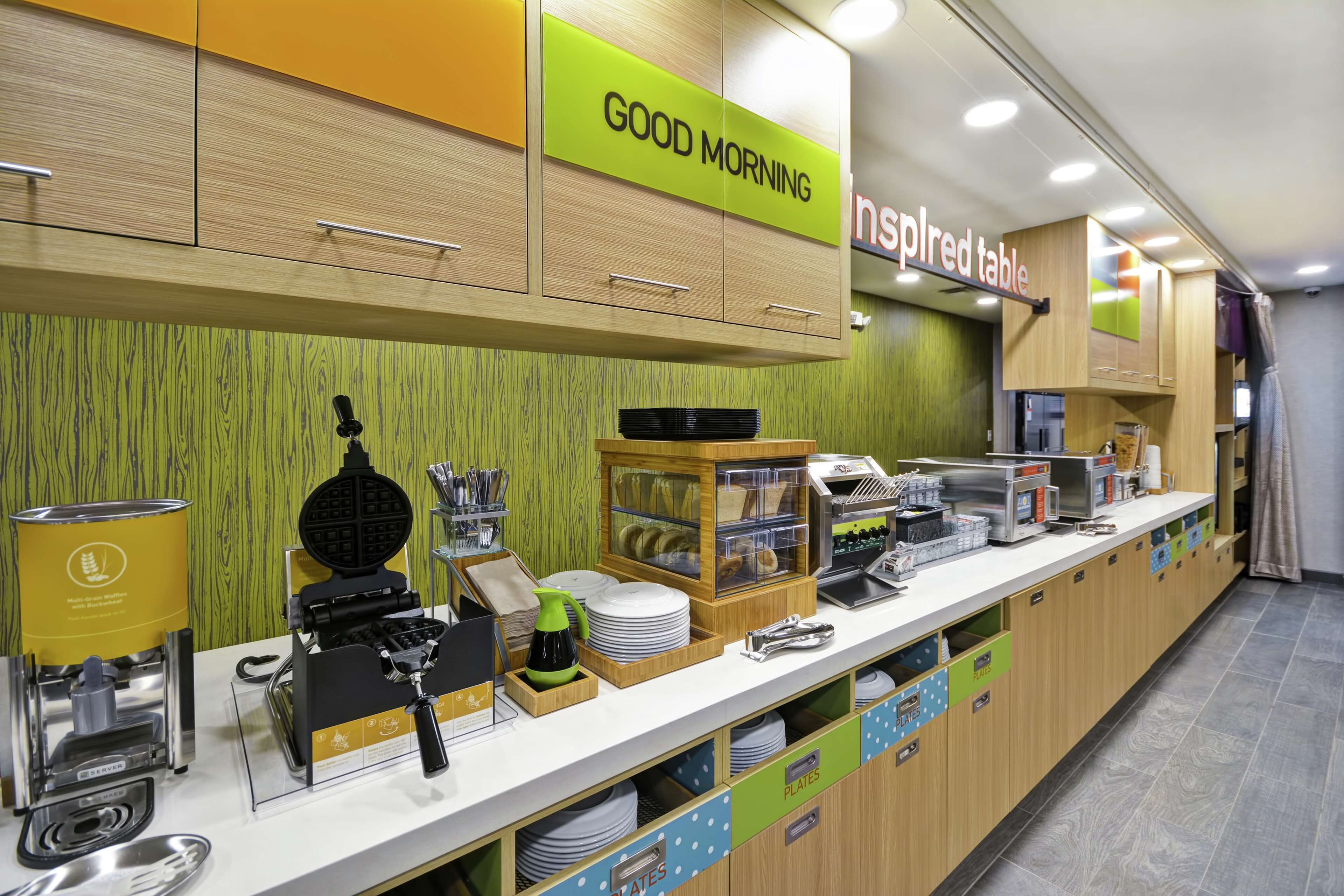Un bar pour le petit-déjeuner équipé d’une machine à café, d’un appareil à gaufres et de divers aliments pour le petit-déjeuner.