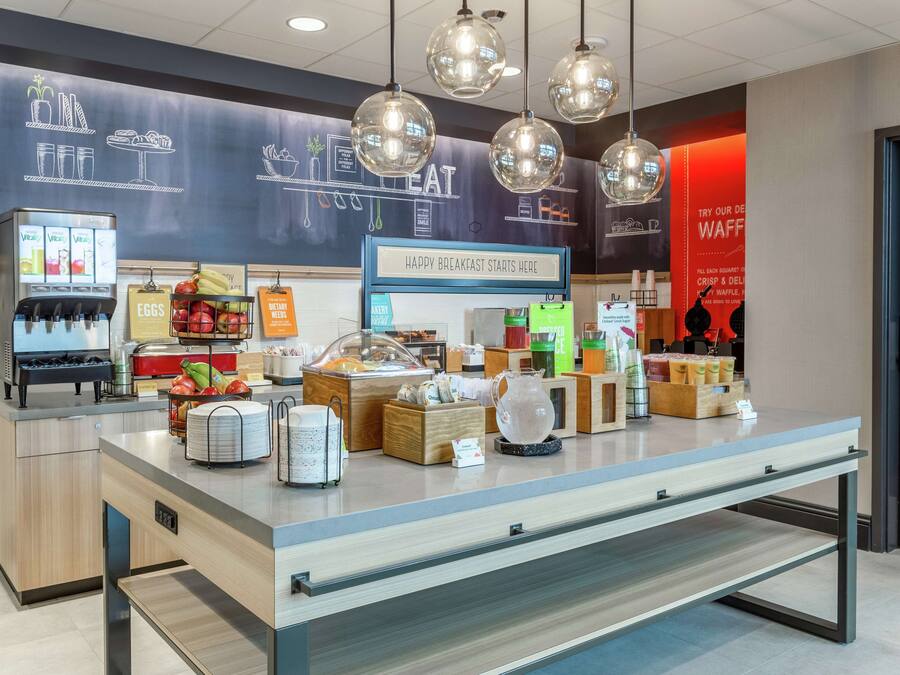 A breakfast area with a counter, beverage dispensers, and a variety of food items.