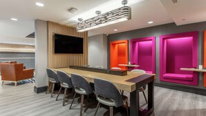 A modern conference room with a long table, six chairs, a flat-screen TV, and vibrant pink accent walls. - Hampton Inn Oakland Downtown-City Center (Oakland)