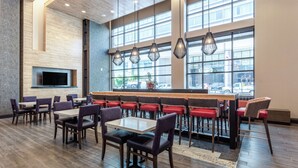 A restaurant with a bar area, multiple tables and chairs, and large windows offering a view of the street. - Hampton Inn Oakland Downtown-City Center (Oakland)