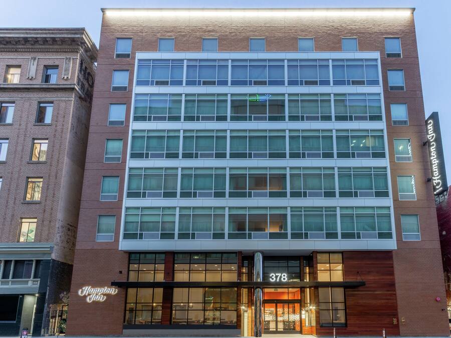 Un hôtel moderne avec une façade en briques, de grandes fenêtres et une entrée imposante.