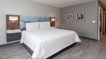 A hotel room with a large bed, two bedside tables with lamps, a wall-mounted map, and two framed pictures.