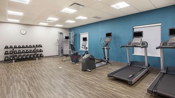 Un gimnasio con cintas de correr, elípticas y mancuernas.