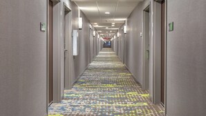 A long, narrow hotel corridor with doors on both sides, a patterned carpet, and overhead lighting. - Hampton Inn Simpsonville (Simpsonville)