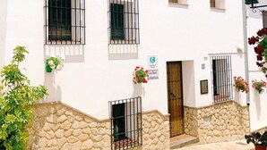 A white building with multiple windows and a stone base. - IDEAL RURAL HOUSING TO ENJOY PEACE AND TRANQUILITY (EL GASTOR)