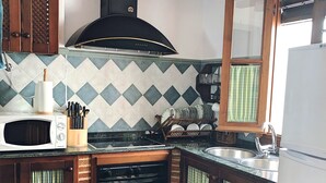 A kitchen with a microwave, stove, sink, and wooden cabinets. - IDEAL RURAL HOUSING TO ENJOY PEACE AND TRANQUILITY (EL GASTOR)