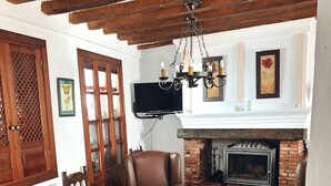 A living room with a fireplace, leather sofas, a glass-top coffee table, and a TV mounted on the wall. - IDEAL RURAL HOUSING TO ENJOY PEACE AND TRANQUILITY (EL GASTOR)
