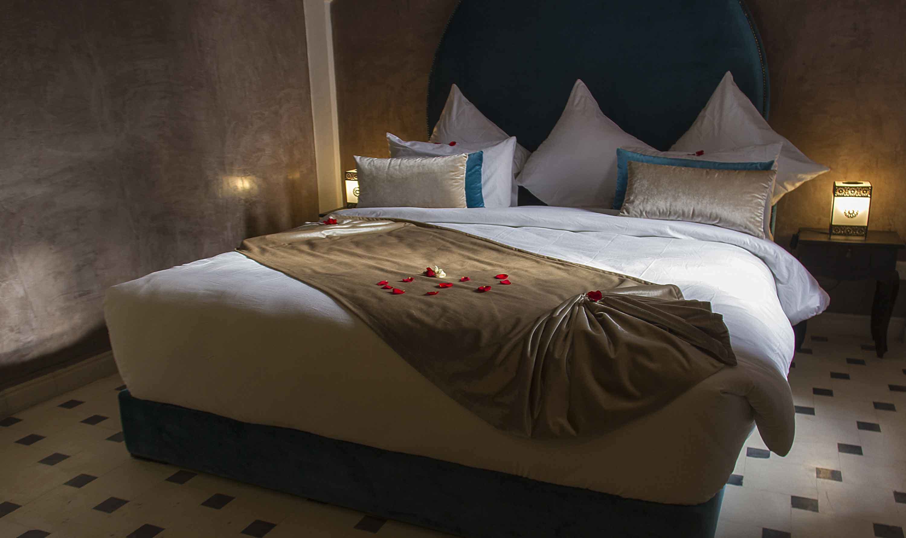 A neatly made bed with a brown throw, white pillows, and a headboard with a teal accent.
