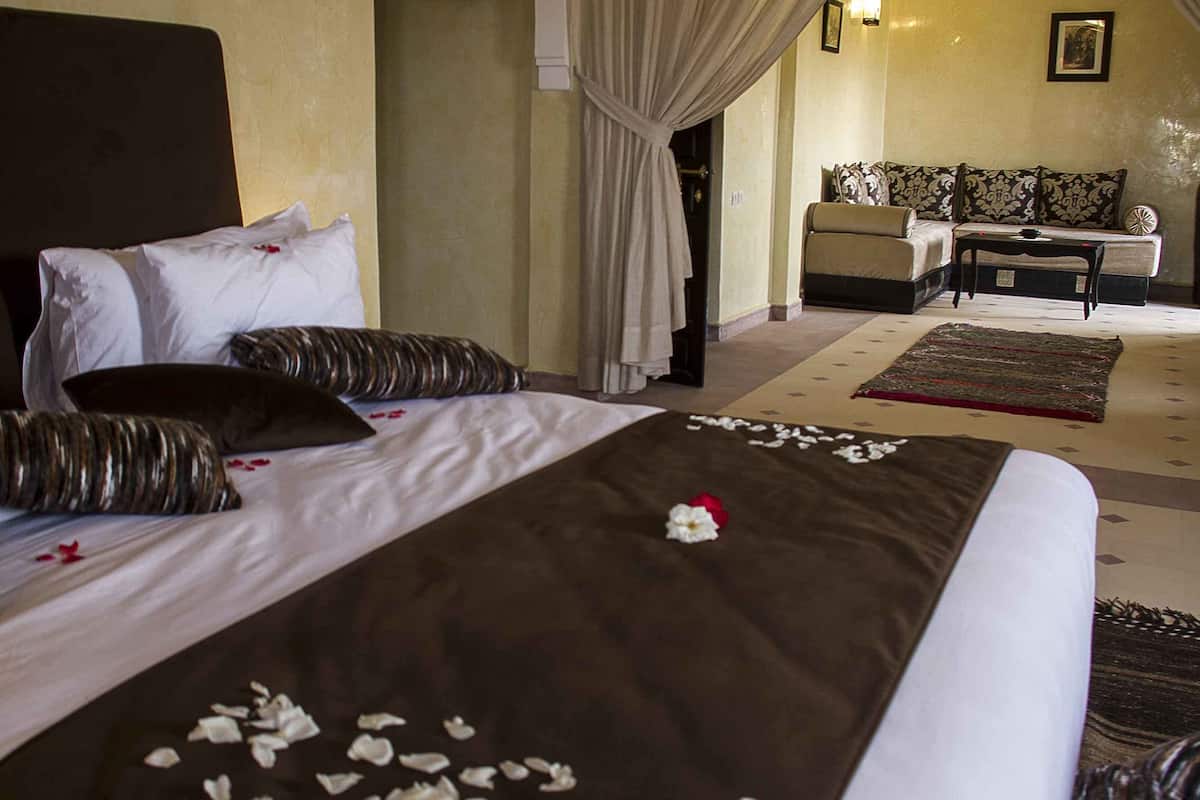 A hotel room with a large bed, a sofa, and a small table.