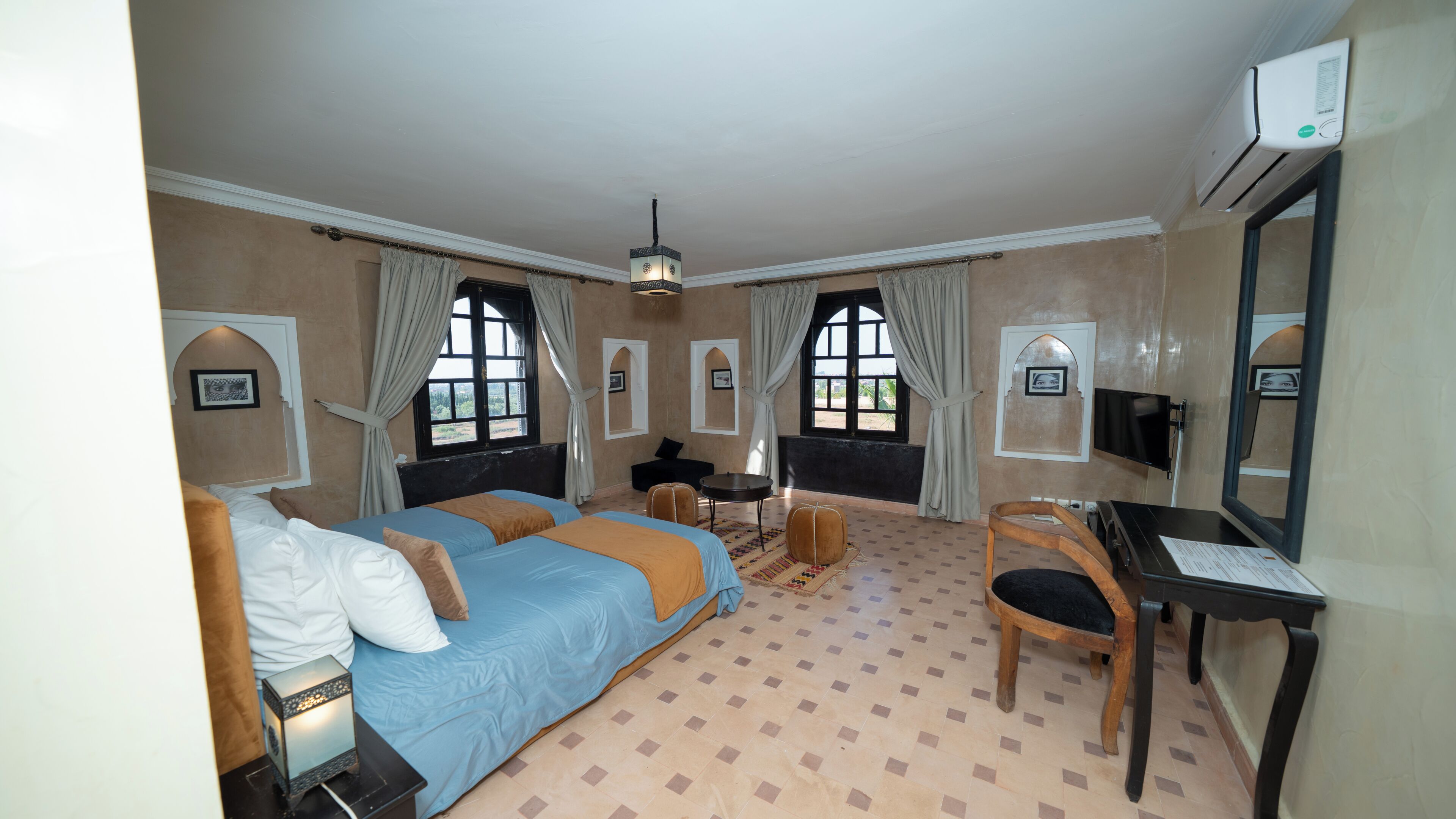 Une chambre d’hôtel avec deux lits, un bureau, une chaise, une télévision et une fenêtre avec des rideaux.