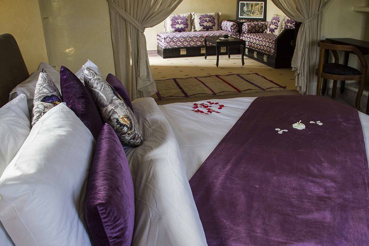 A hotel room with a large bed, a sofa set, a small table, and a chair.