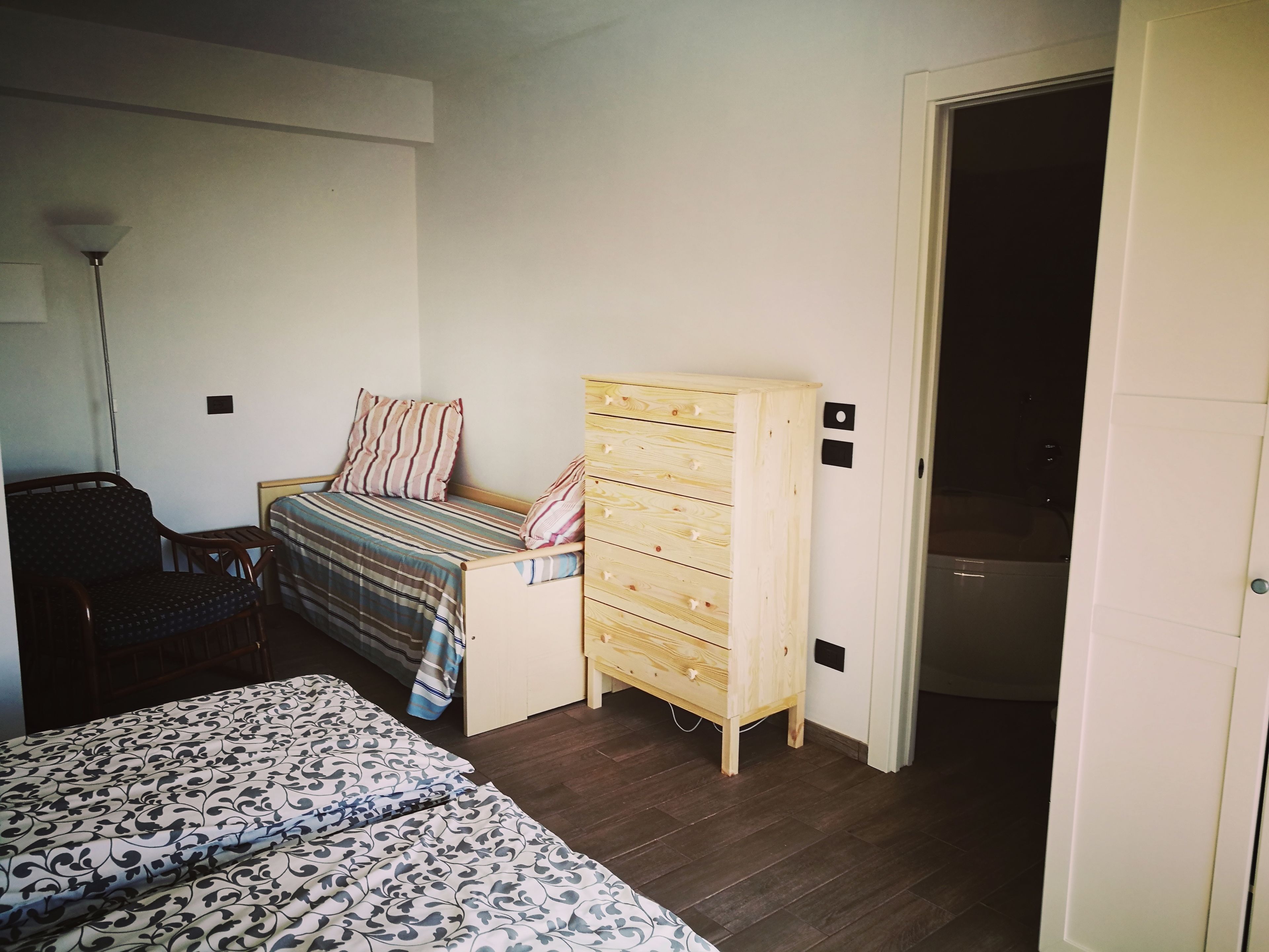 Une chambre à coucher avec un lit, une commode en bois, une chaise et une lampe.