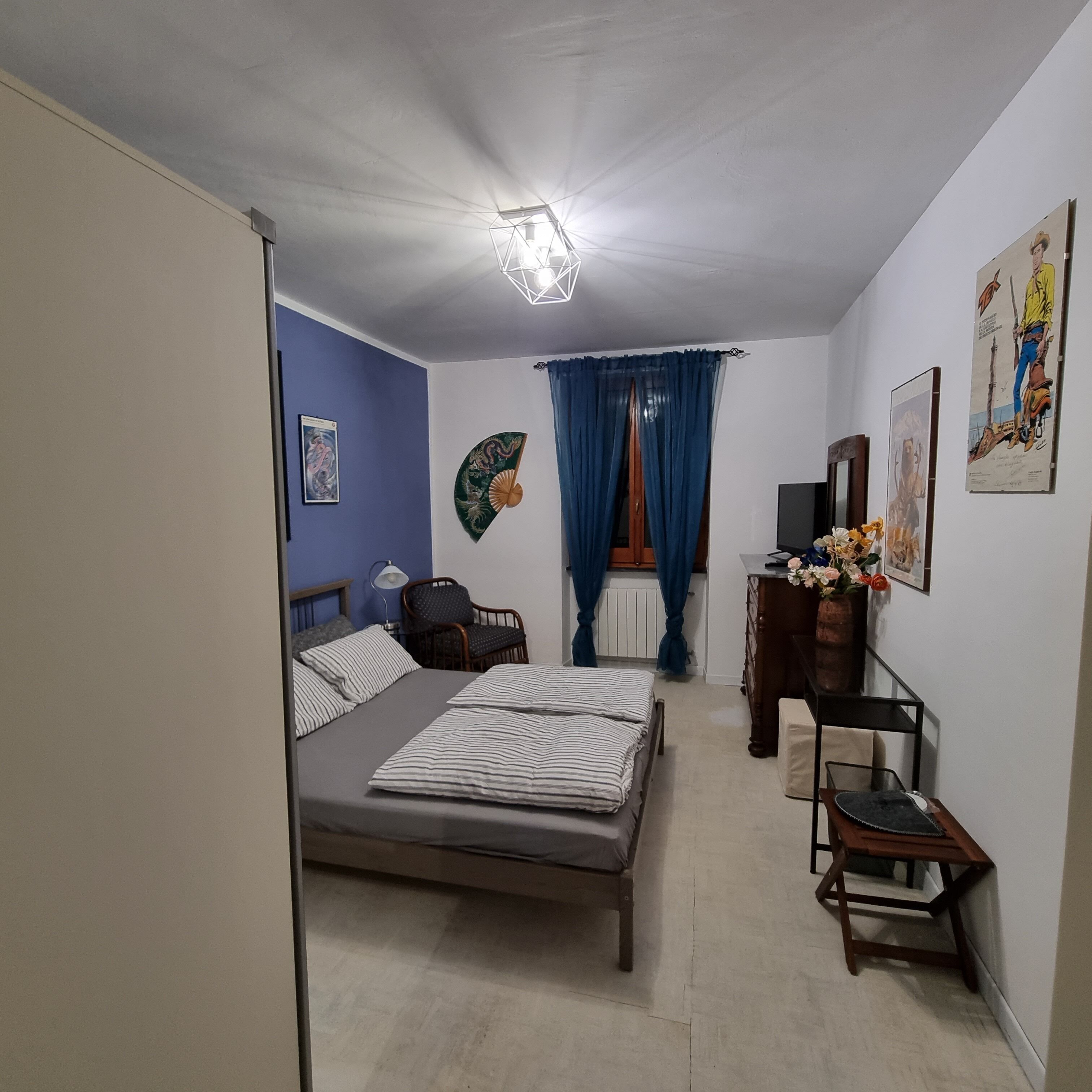 Un dormitorio con cama, una silla, un aparador y un escritorio.